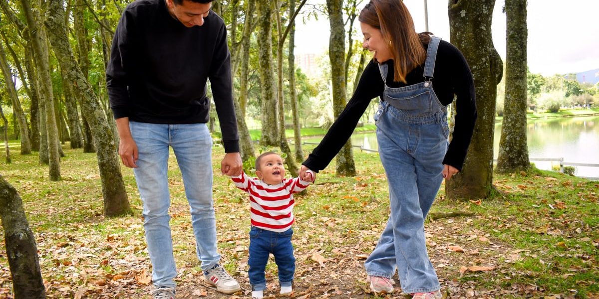 A joyful family enjoys a walk under lush green trees in the park.