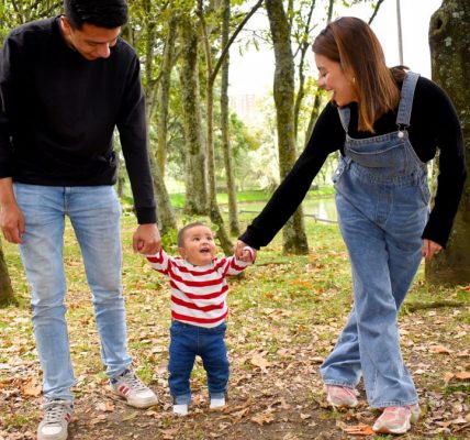 A joyful family enjoys a walk under lush green trees in the park.