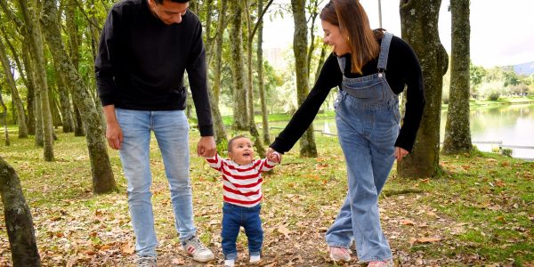 A joyful family enjoys a walk under lush green trees in the park.