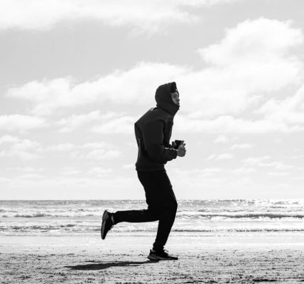 Silhouette of a jogger running along La Lucila del Mar beach, captured in monochrome.